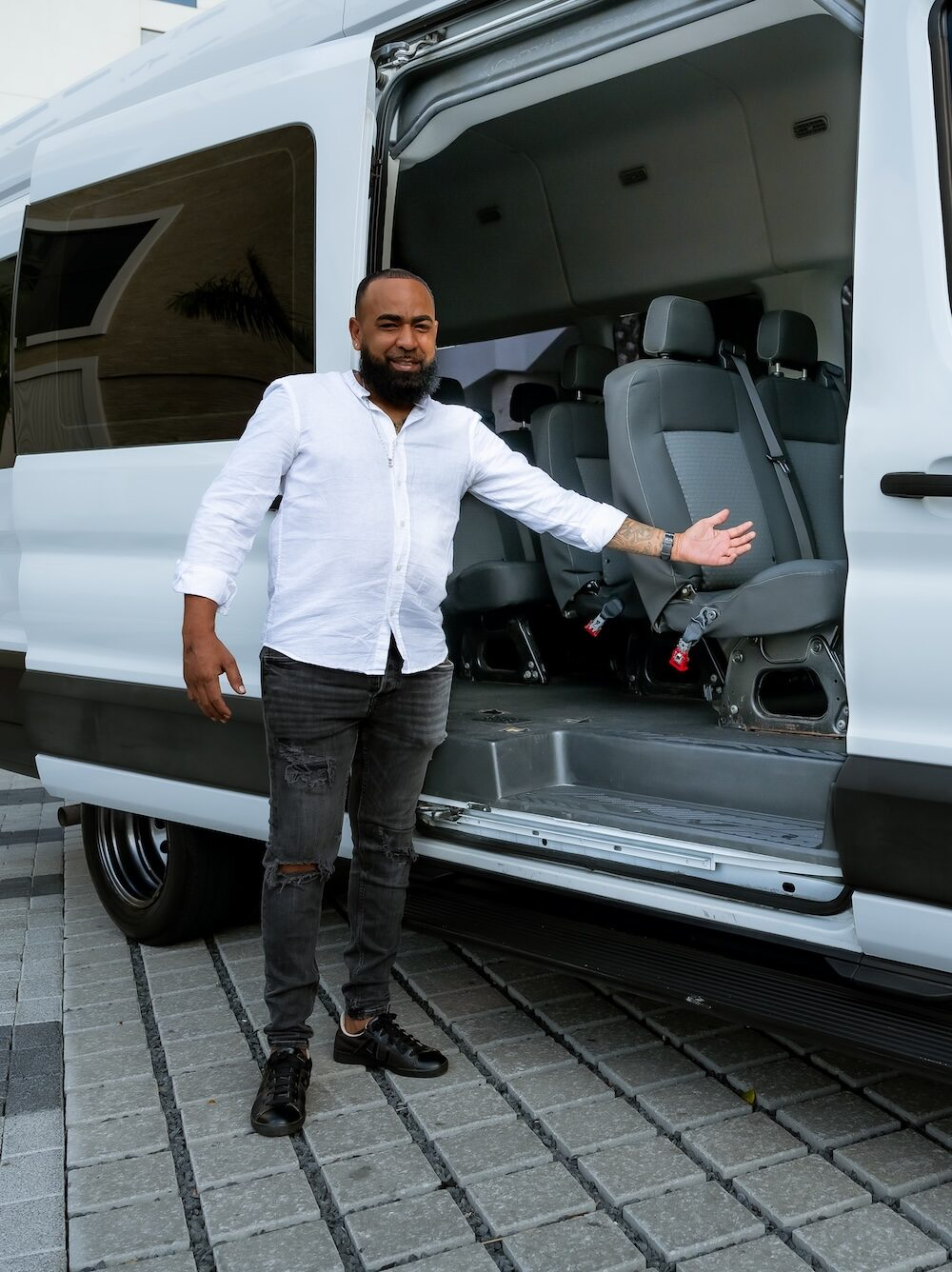 Aruba First Choice driver welcoming guests beside an open passenger van